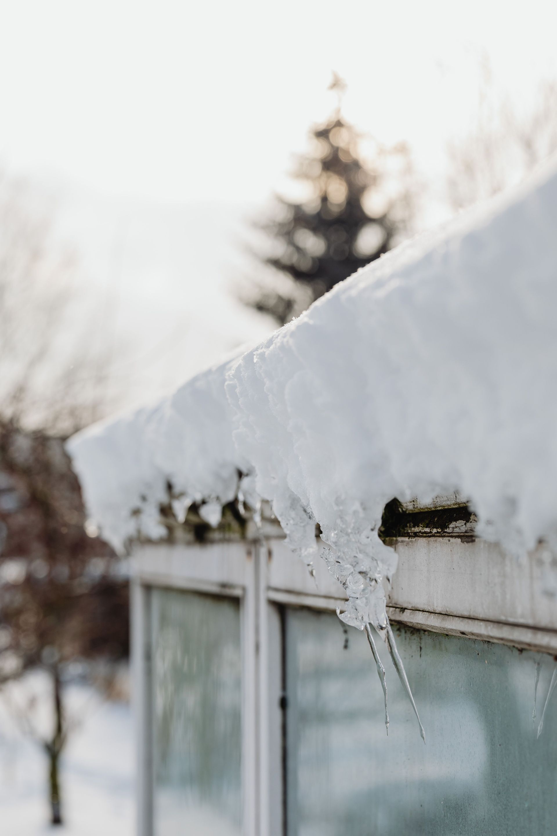 Close-up of a snowy roof with icicles, showcasing winter's cold beauty outdoors.