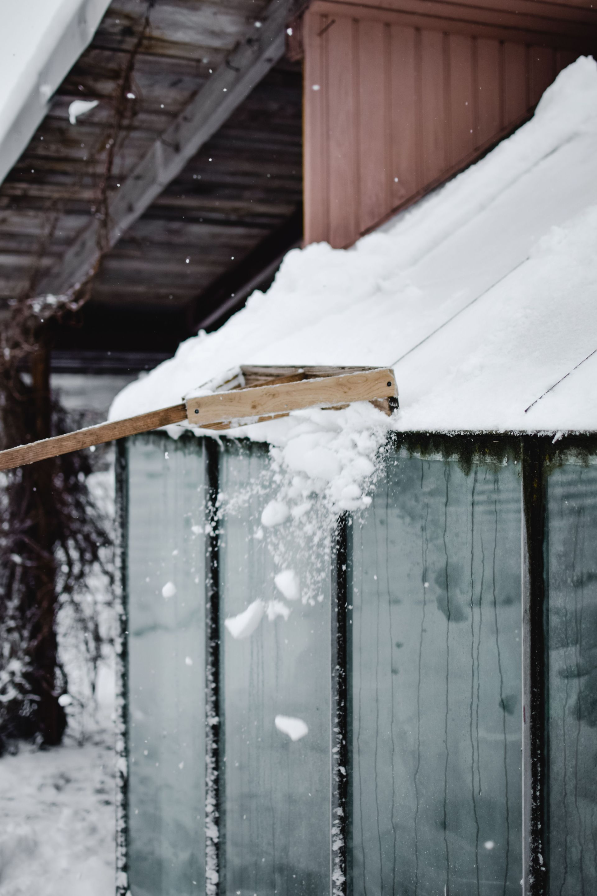 Snow being removed from a shed roof in snowy Estonian winter landscape.